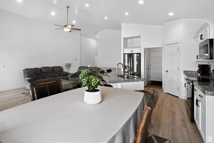 Dining space featuring light wood finished floors, recessed lighting, a ceiling fan, and high vaulted ceiling