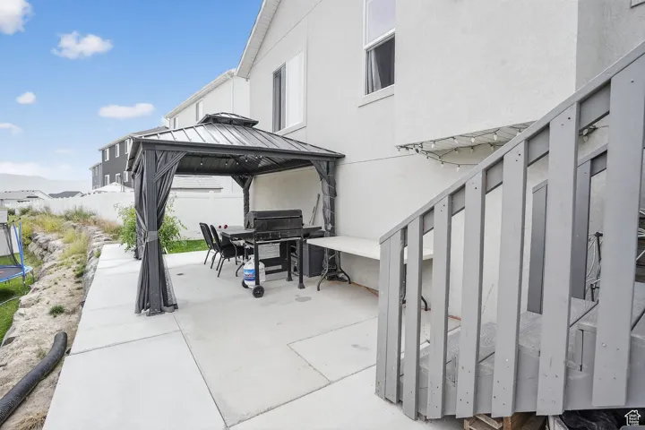 View of patio / terrace featuring a gazebo, area for grilling, outdoor dining space, and a trampoline