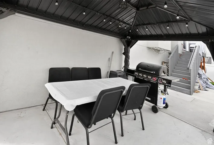 View of patio with outdoor dining space, area for grilling, a gazebo, and stairs