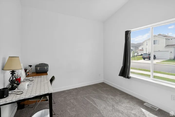 Office space with lofted ceiling, light carpet, and a residential view