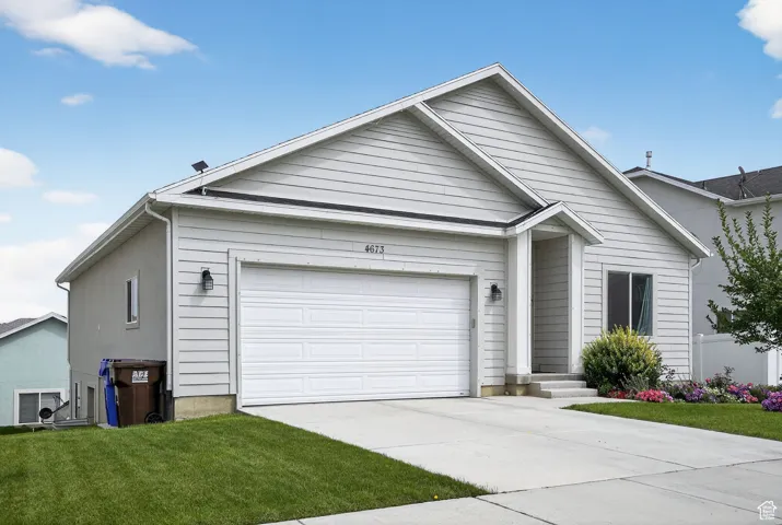 Ranch-style house featuring driveway, an attached garage, and a front yard