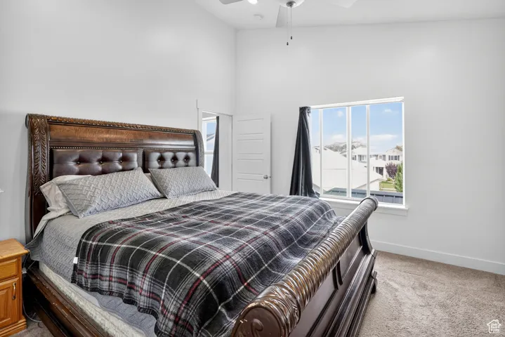 Bedroom featuring light carpet, a towering ceiling, and a ceiling fan