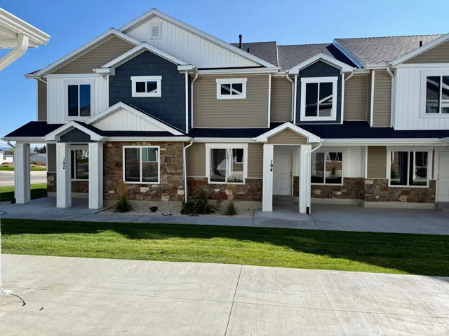 Craftsman-style home featuring board and batten siding, stone siding, and a front lawn