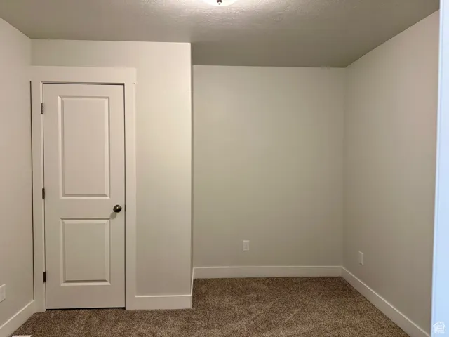 Carpeted spare room featuring baseboards and a textured ceiling