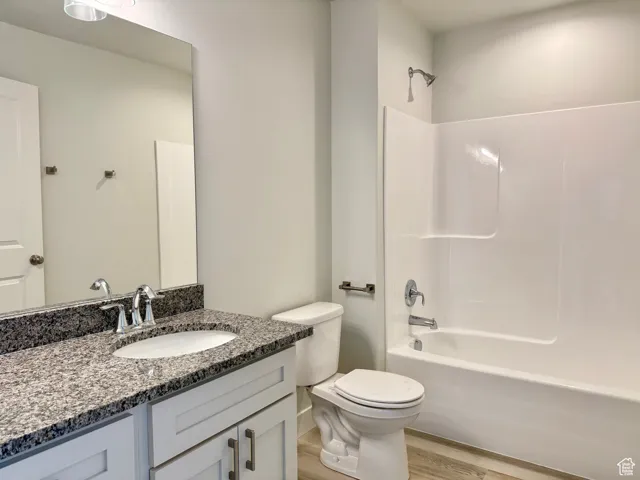 Full bathroom with shower / washtub combination, vanity, and light wood-type flooring