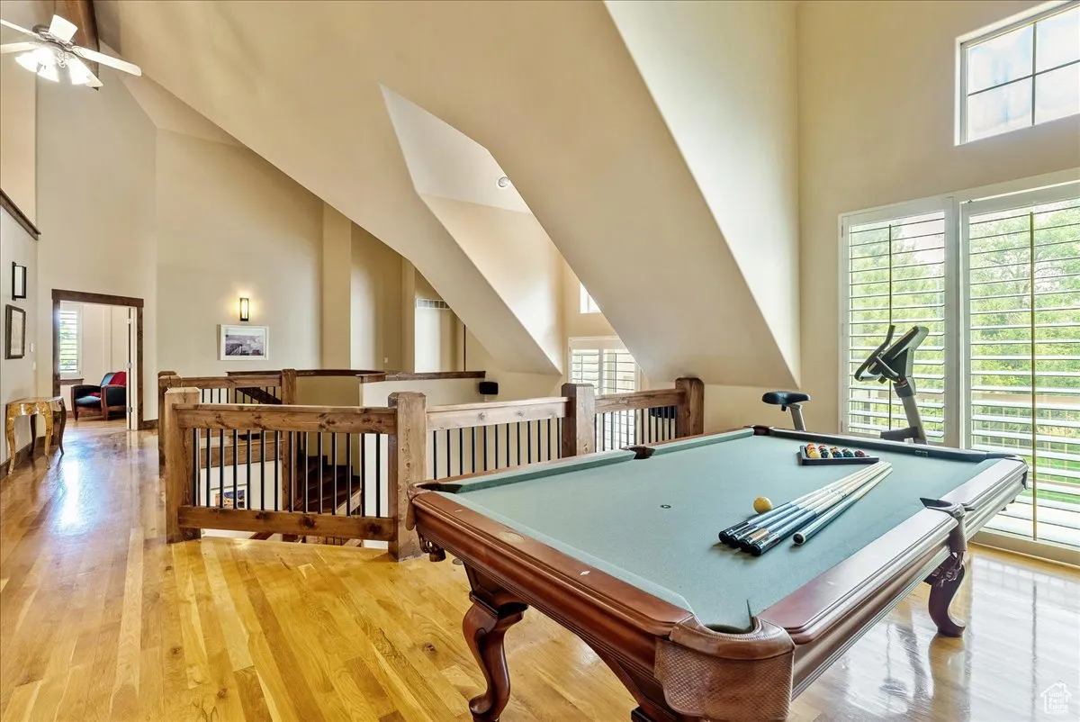 Game room with high vaulted ceiling, light wood finished floors, billiards table, and a ceiling fan