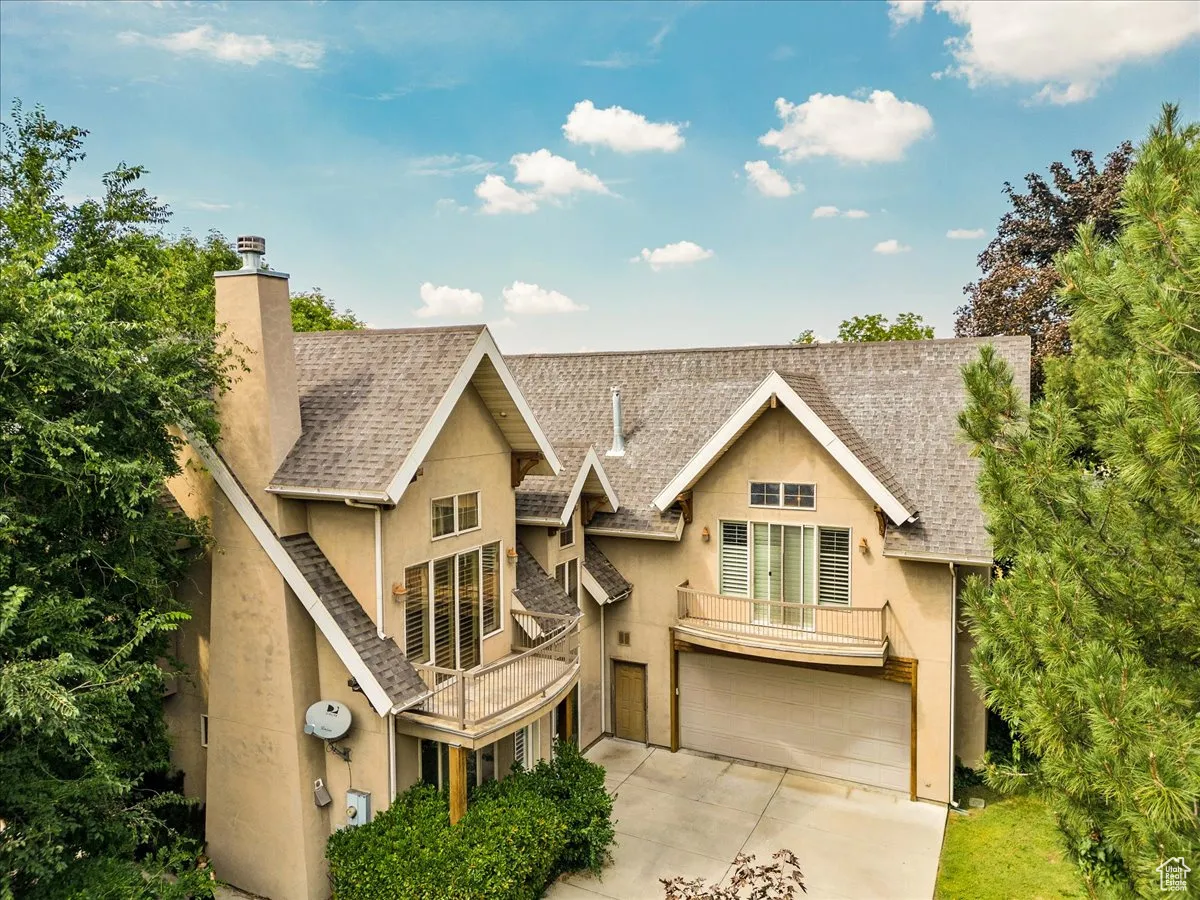 Chalet / cabin featuring stucco siding, a chimney, an attached garage, and concrete driveway