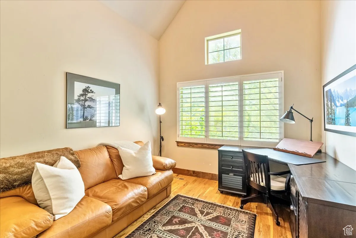 Home office with light wood-type flooring and high vaulted ceiling