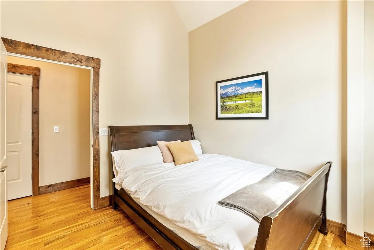 Bedroom with light wood-type flooring and lofted ceiling