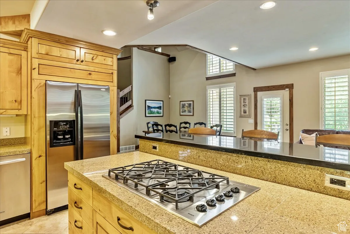 Kitchen featuring appliances with stainless steel finishes, recessed lighting, open floor plan, light brown cabinetry, and tile countertops