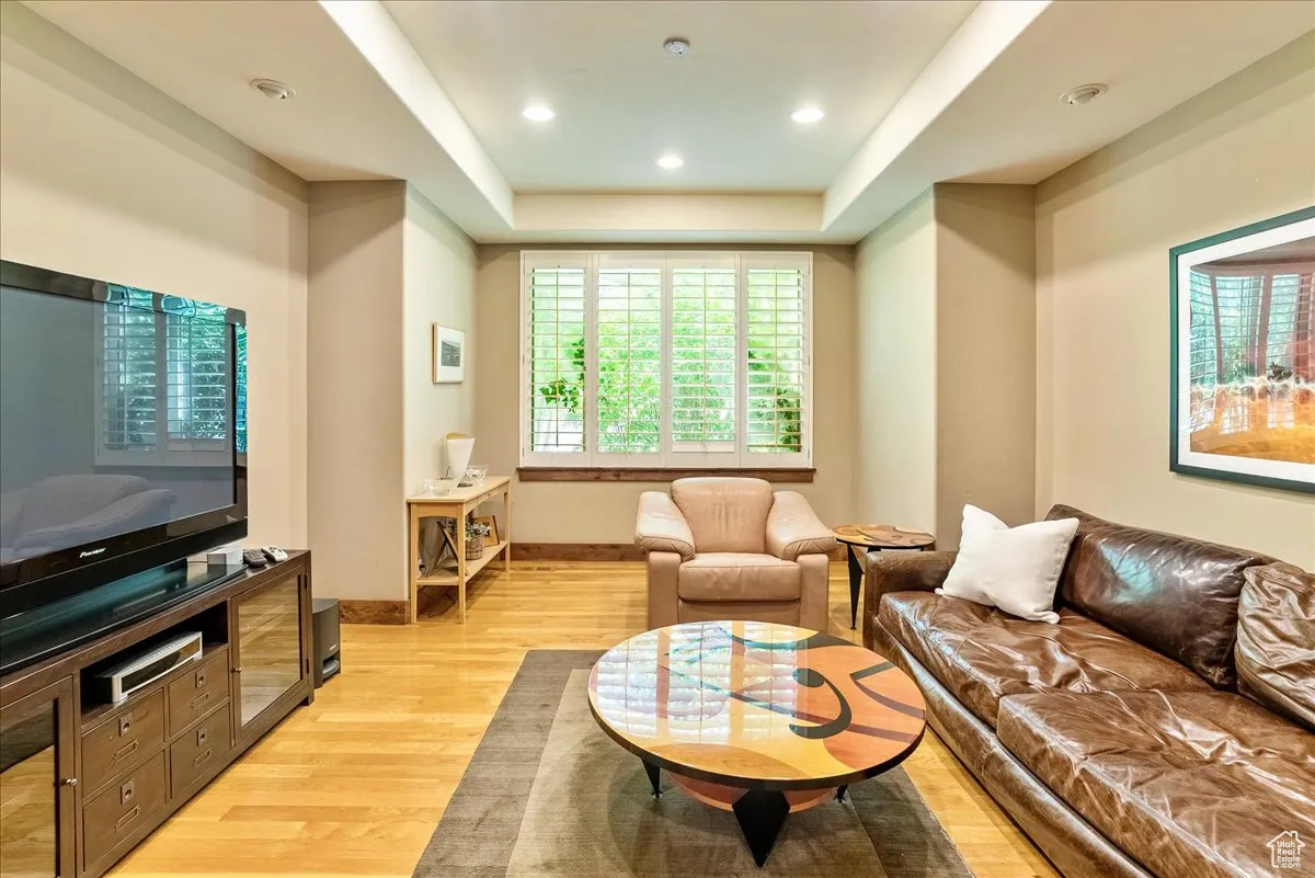 Living room featuring light wood finished floors, a tray ceiling, and recessed lighting
