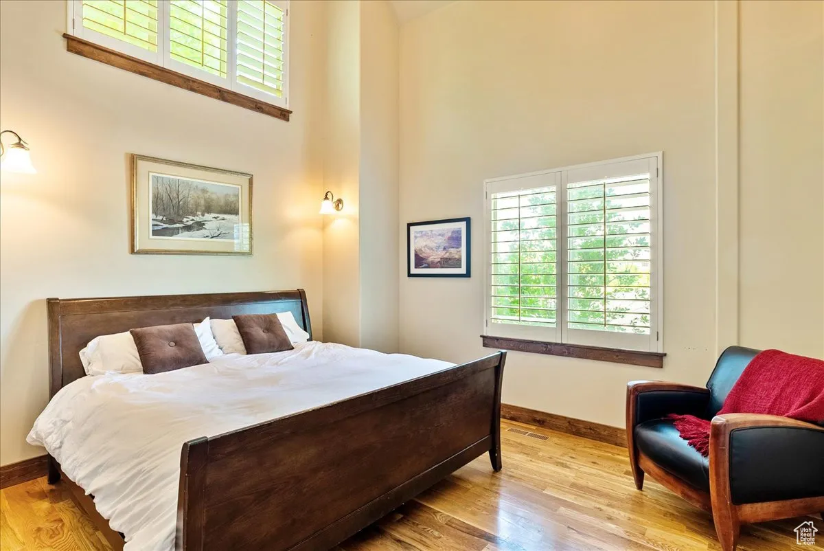 Bedroom featuring multiple windows, wood finished floors, and a high ceiling