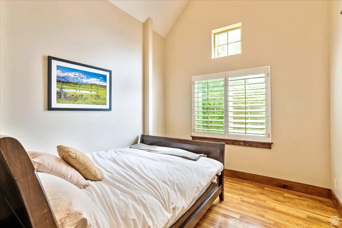 Bedroom featuring wood finished floors and high vaulted ceiling