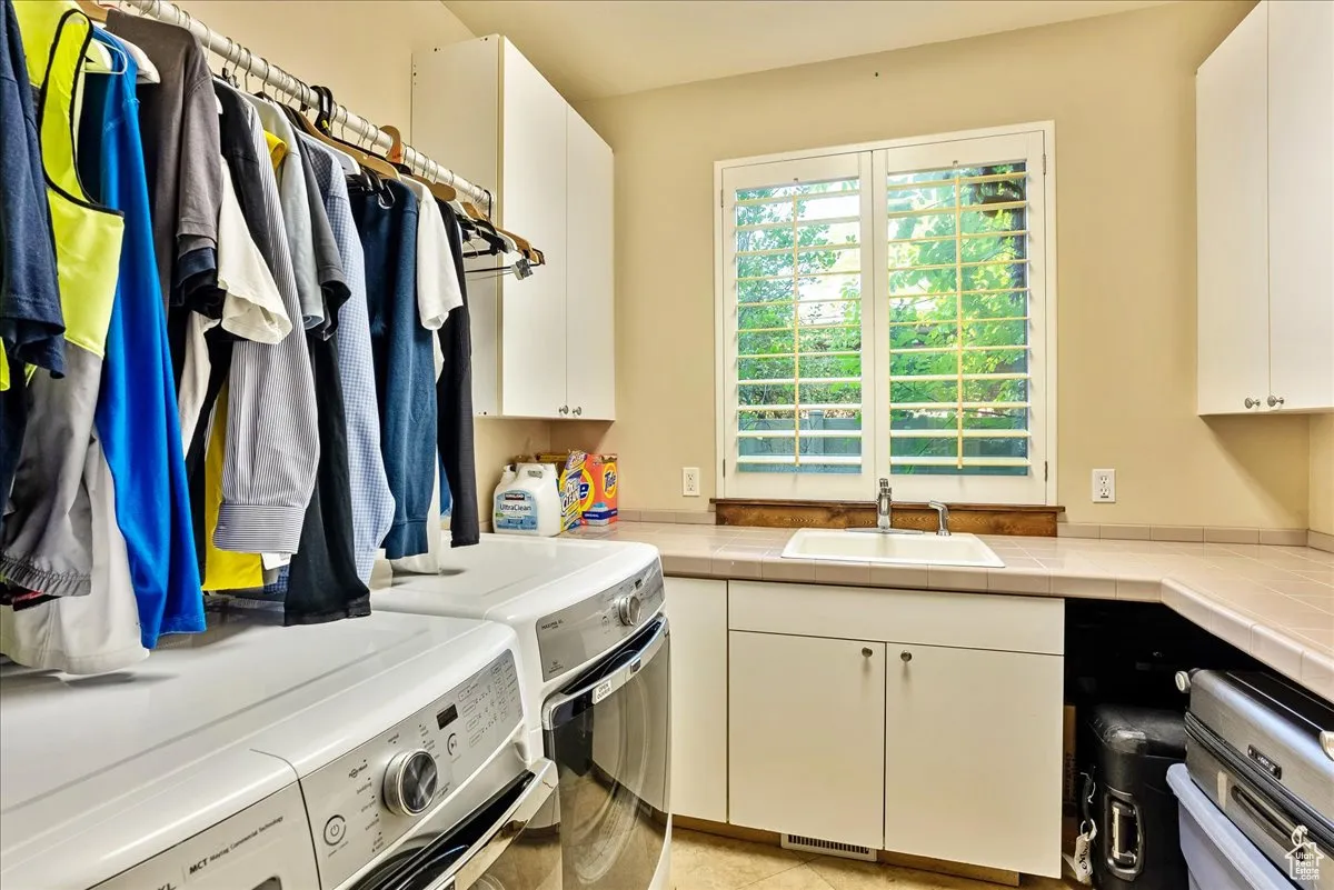 Laundry area featuring washer and dryer, cabinet space, and light tile patterned floors