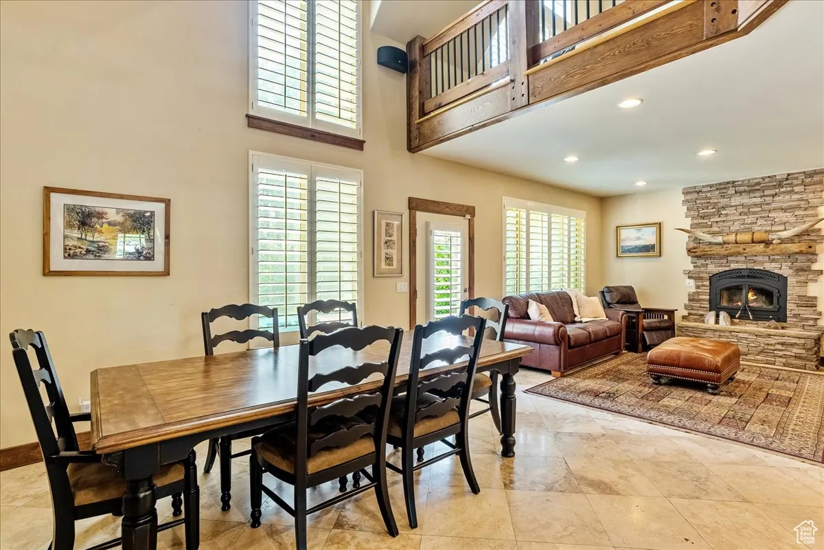 Dining area with a fireplace, recessed lighting, a towering ceiling, and light tile patterned floors