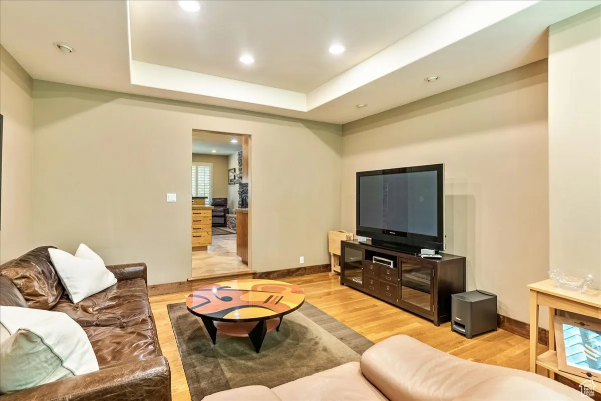 Living room featuring recessed lighting, light wood-style floors, and a raised ceiling