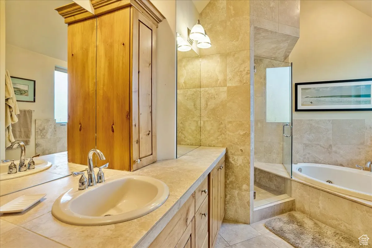 Bathroom with vanity, a tub with jets, a stall shower, tile walls, and light tile patterned flooring