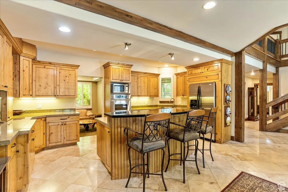 Kitchen featuring a breakfast bar area, beam ceiling, a center island, plenty of natural light, and stainless steel appliances