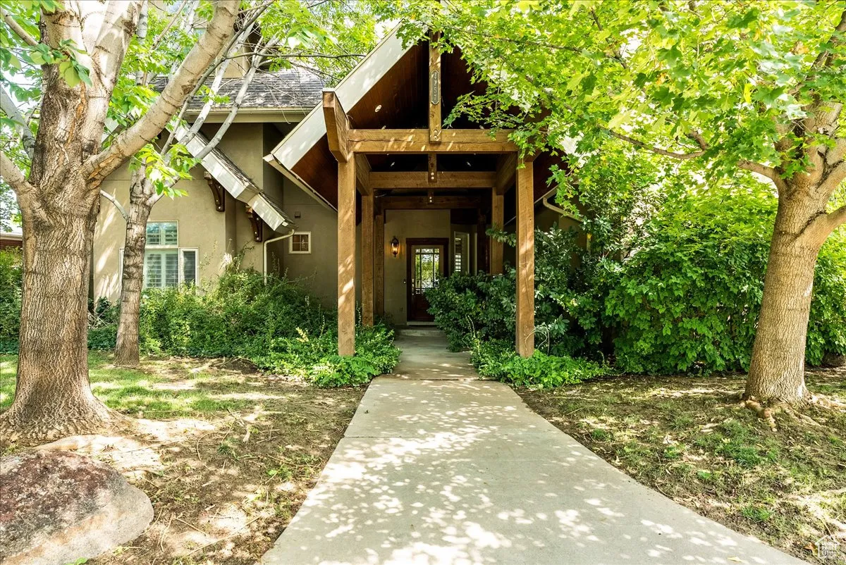 View of exterior entry with stucco siding and a shingled roof