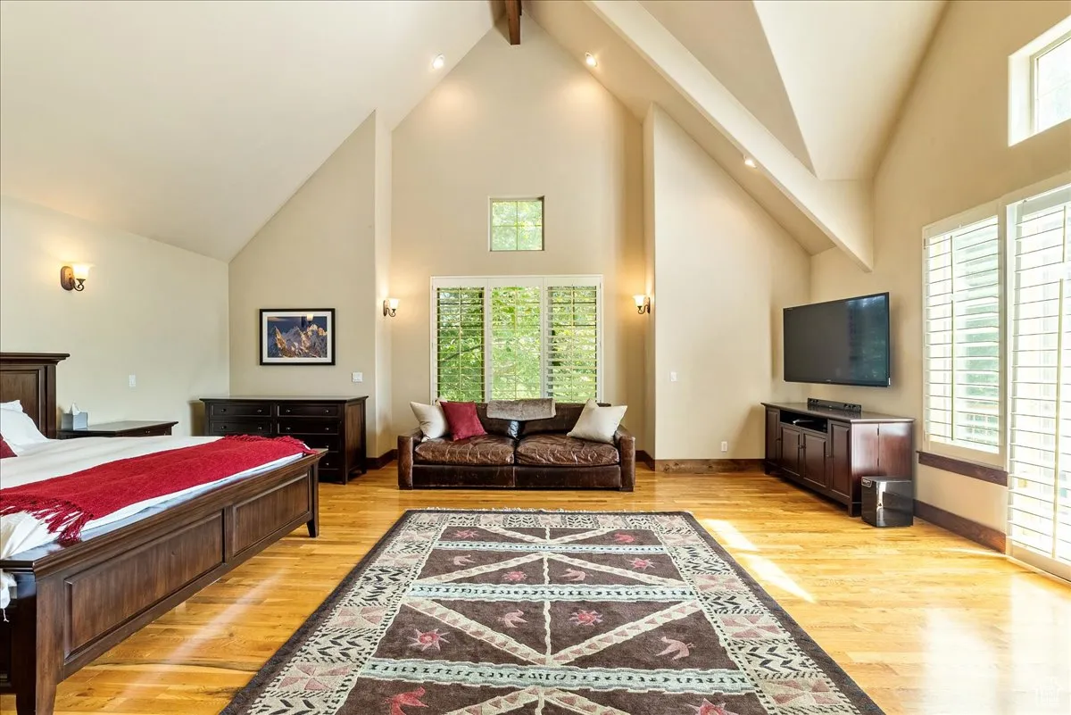 Bedroom with high vaulted ceiling, light wood-type flooring, and beamed ceiling