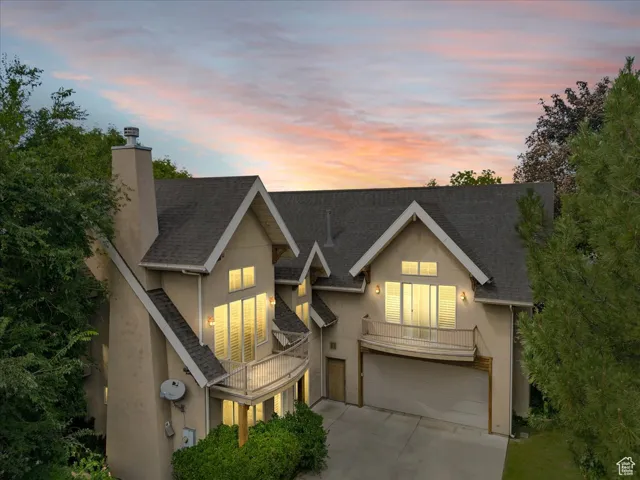 View of front of home featuring stucco siding, driveway, a chimney, and a shingled roof
