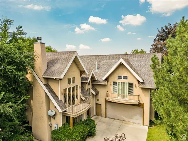 Chalet / cabin featuring stucco siding, a chimney, an attached garage, and concrete driveway
