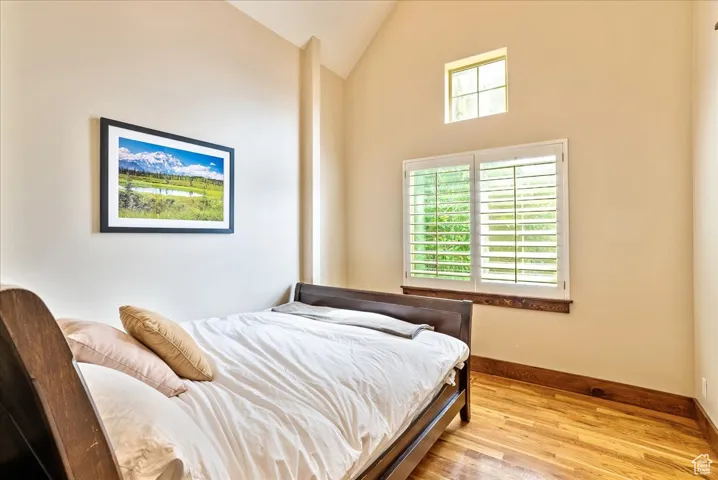 Bedroom featuring wood finished floors and high vaulted ceiling