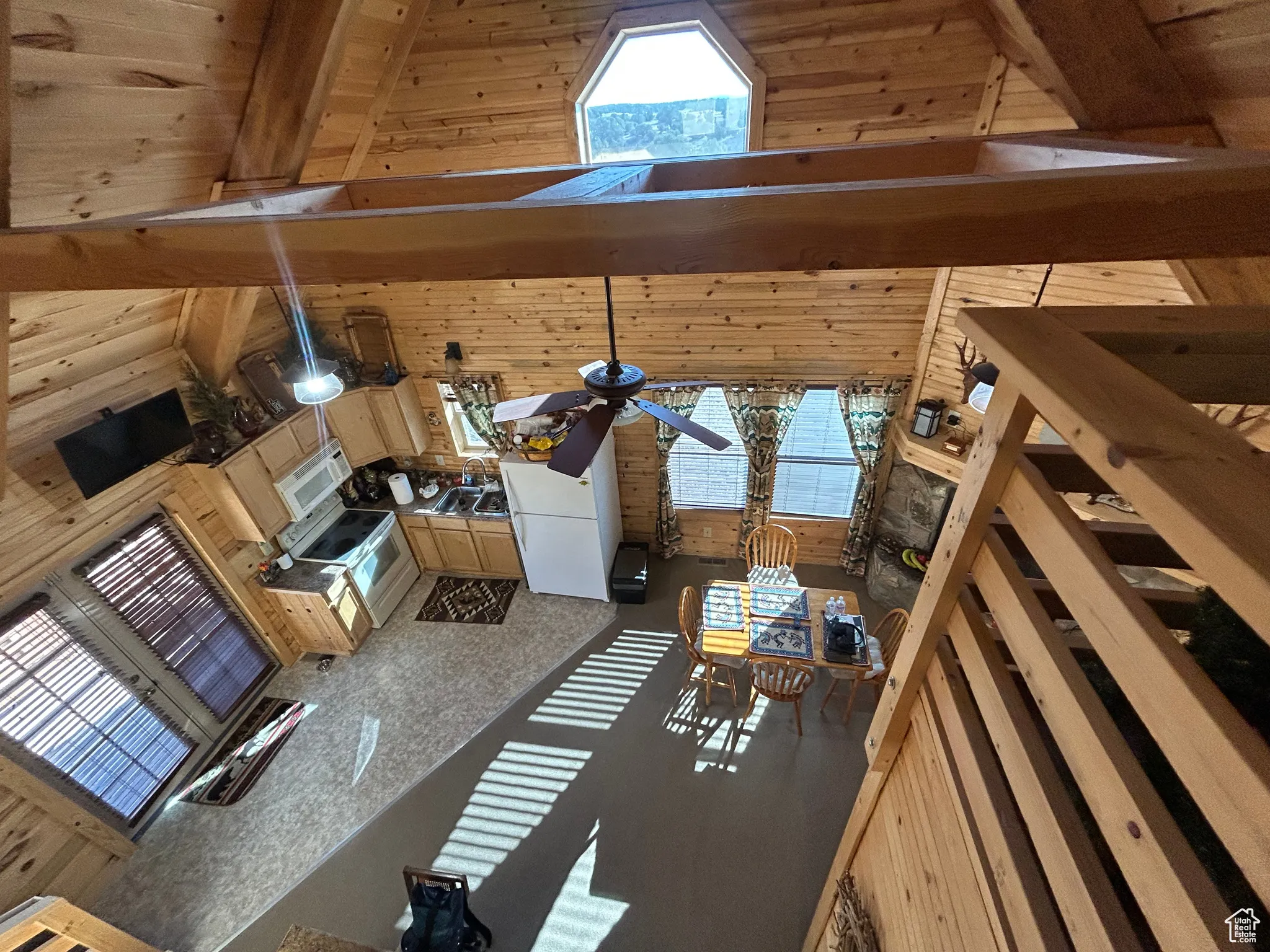 Living area with high vaulted ceiling, a wood ceiling with exposed beams, wooden walls, and a skylight