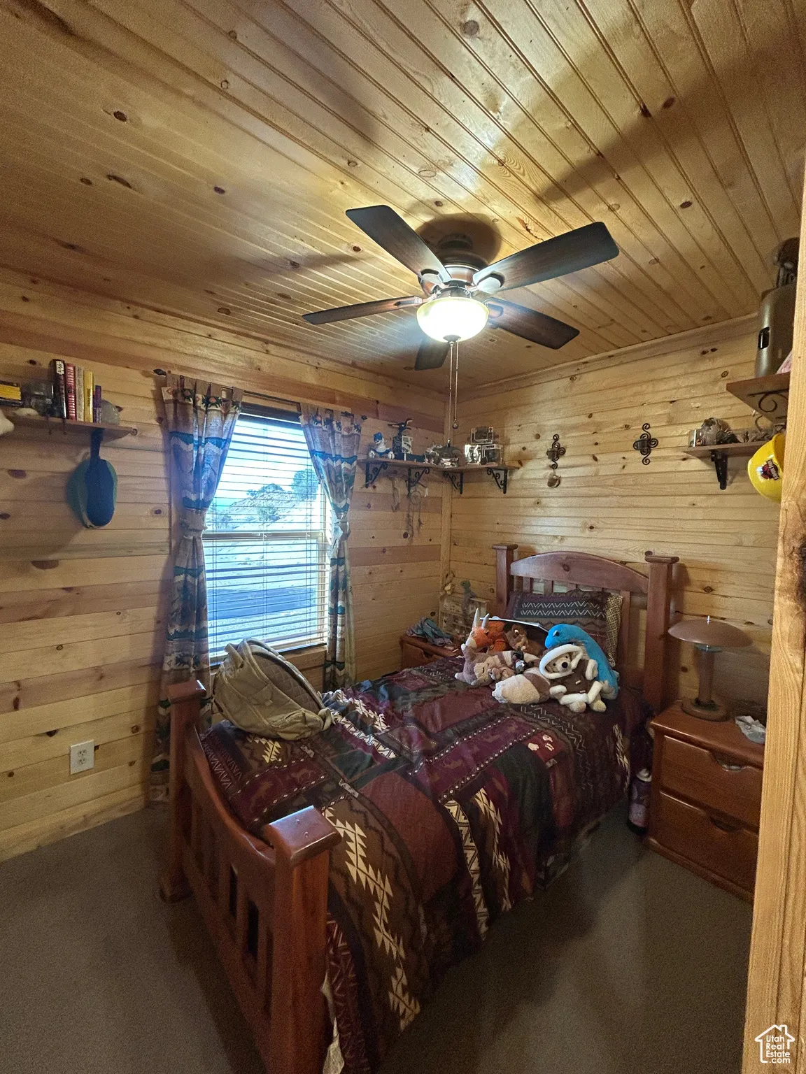 Carpeted bedroom featuring wooden walls, wood ceiling, and a ceiling fan