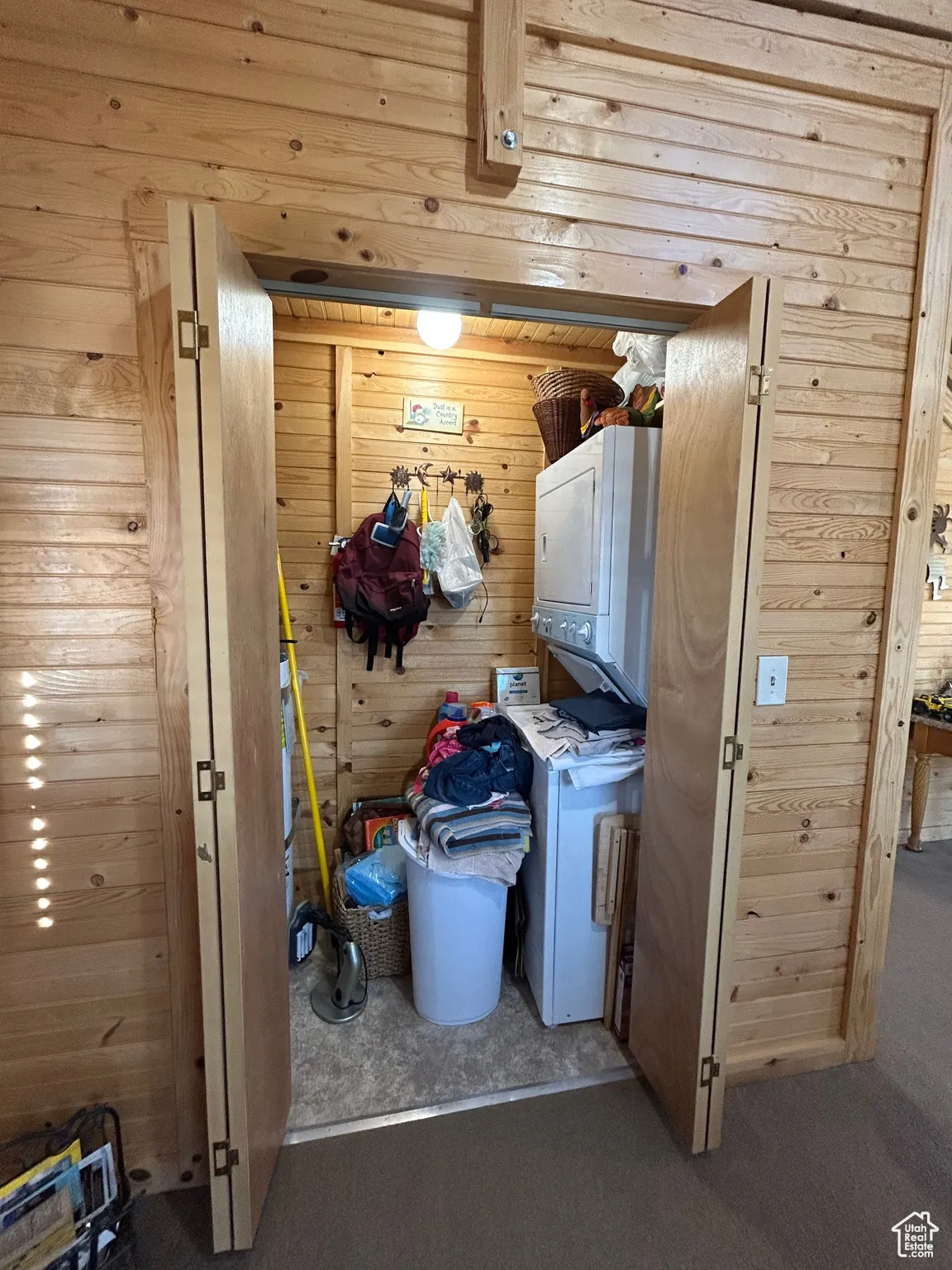 Laundry area featuring wood walls and estacked washer and dryer