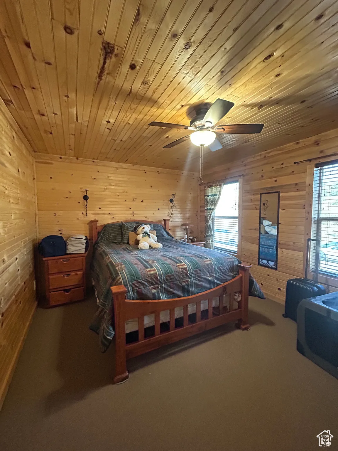 Carpeted bedroom featuring wooden walls, wood ceiling, and ceiling fan
