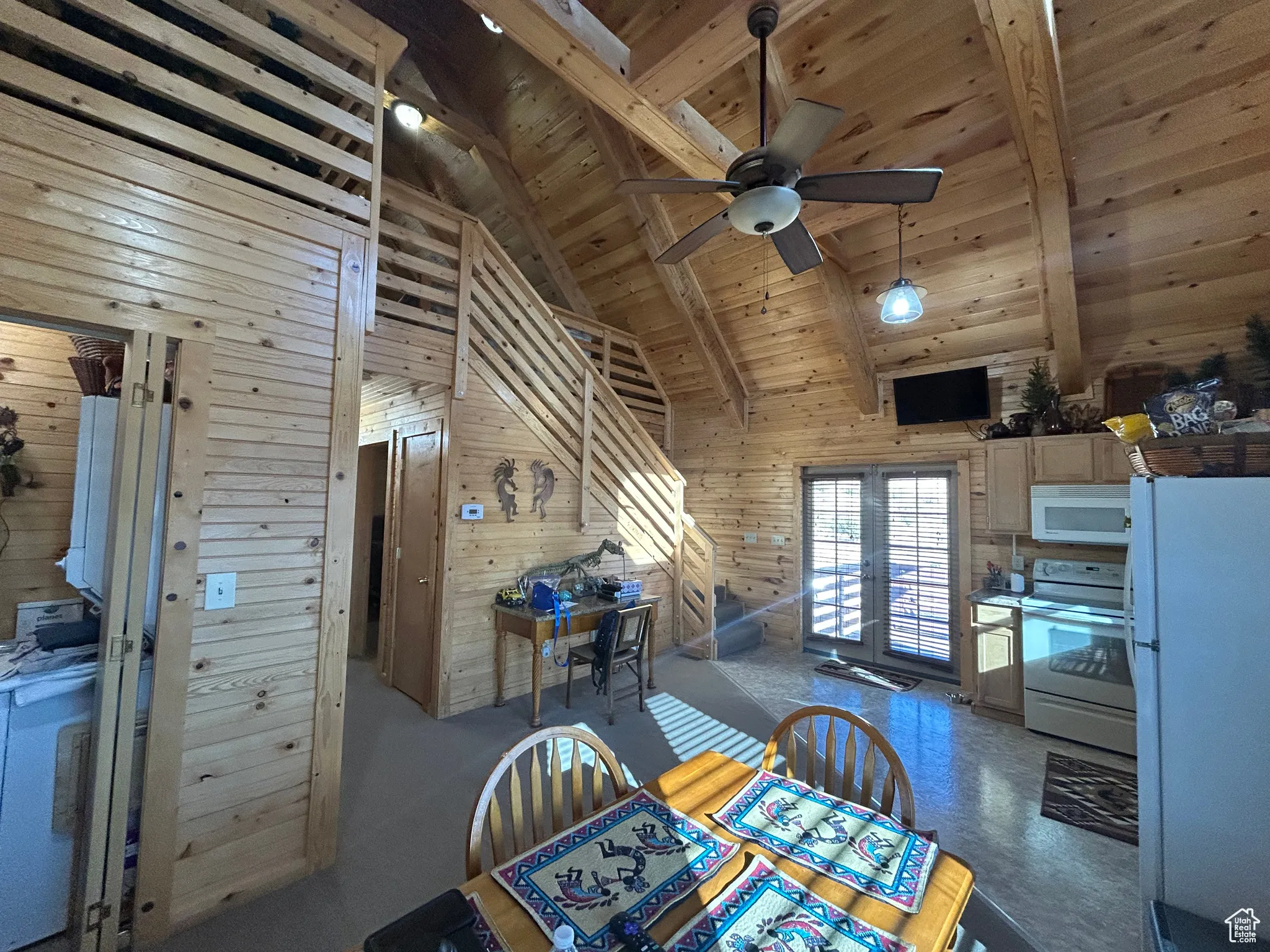 Dining room featuring wooden walls, a wood ceiling with exposed beams, high vaulted ceiling, french doors, and ceiling fan