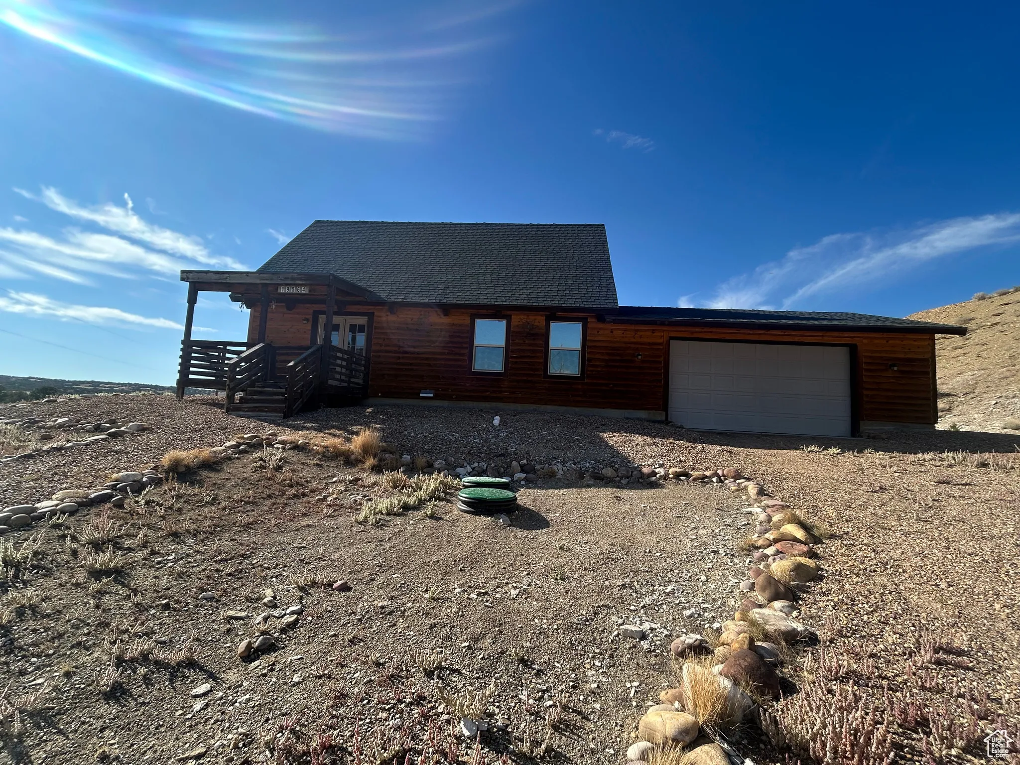 Chalet / cabin with roof with shingles, an attached garage, and driveway