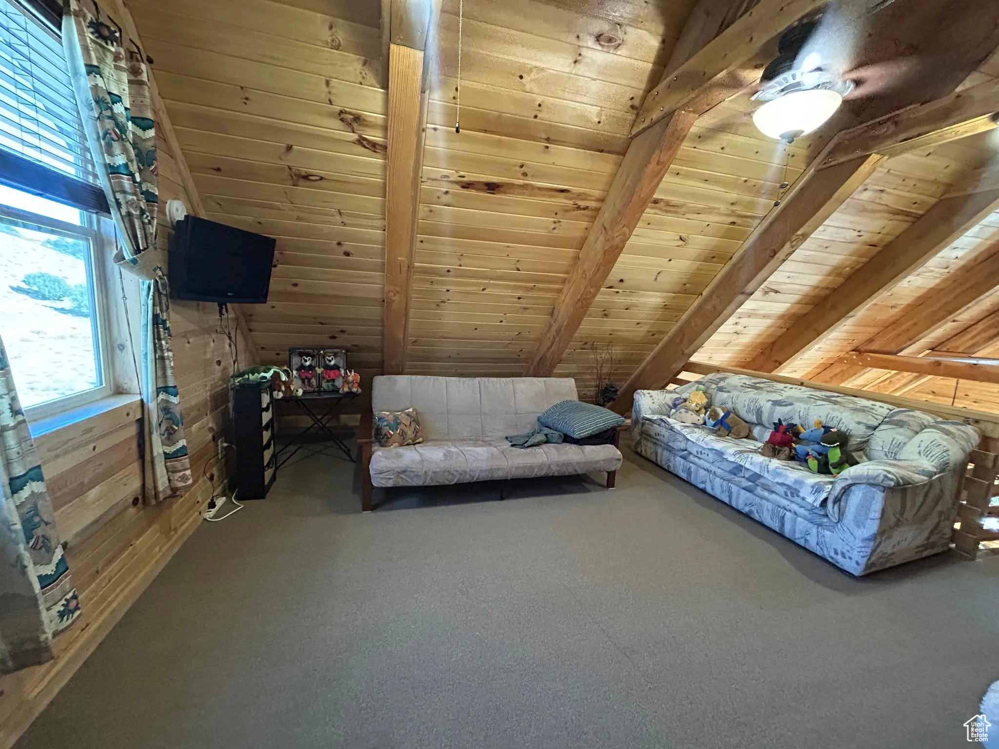 Carpeted bedroom featuring wood ceiling, wood walls, and a ceiling fan