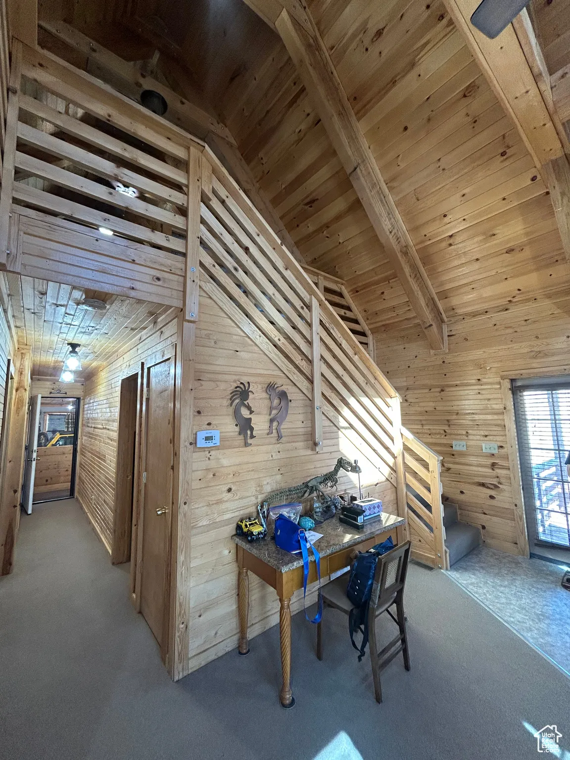 Carpeted office featuring wood walls, a wooden ceiling with exposed beams, and high vaulted ceiling