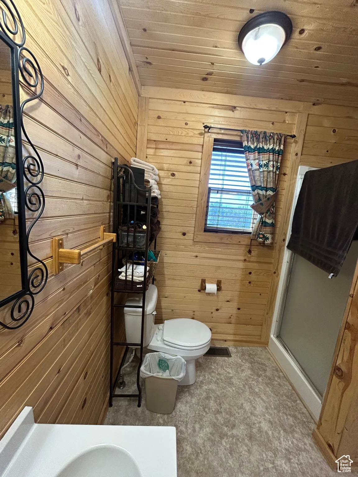 Full bathroom featuring wooden walls, wooden ceiling, and a stall shower