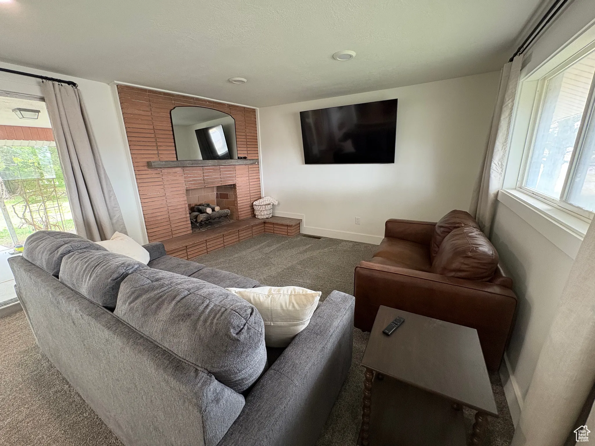 Living room with healthy amount of natural light, a brick fireplace, and carpet flooring