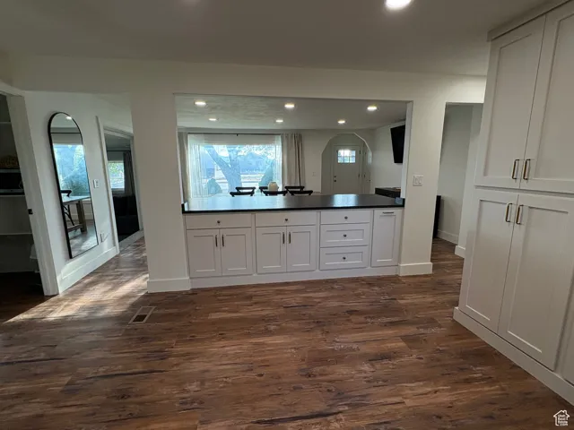 Kitchen with white cabinetry, healthy amount of natural light, dark wood finished floors, recessed lighting, and a peninsula