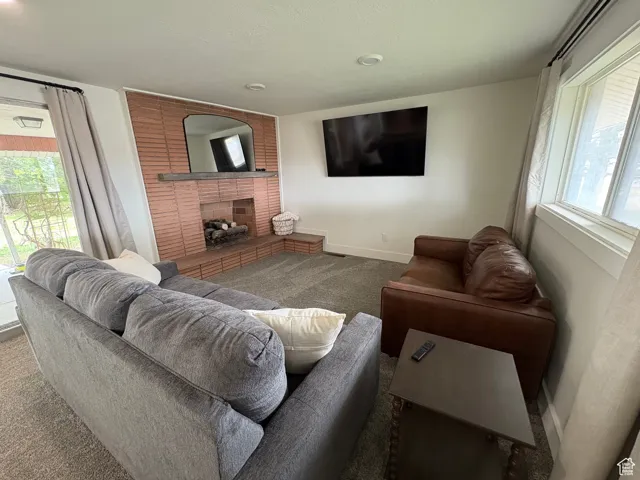 Living room with healthy amount of natural light, a brick fireplace, and carpet flooring