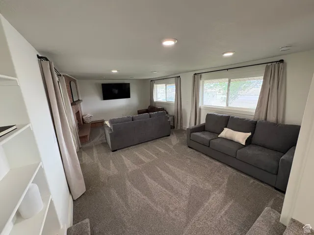 Living room featuring carpet flooring, recessed lighting, and a brick fireplace