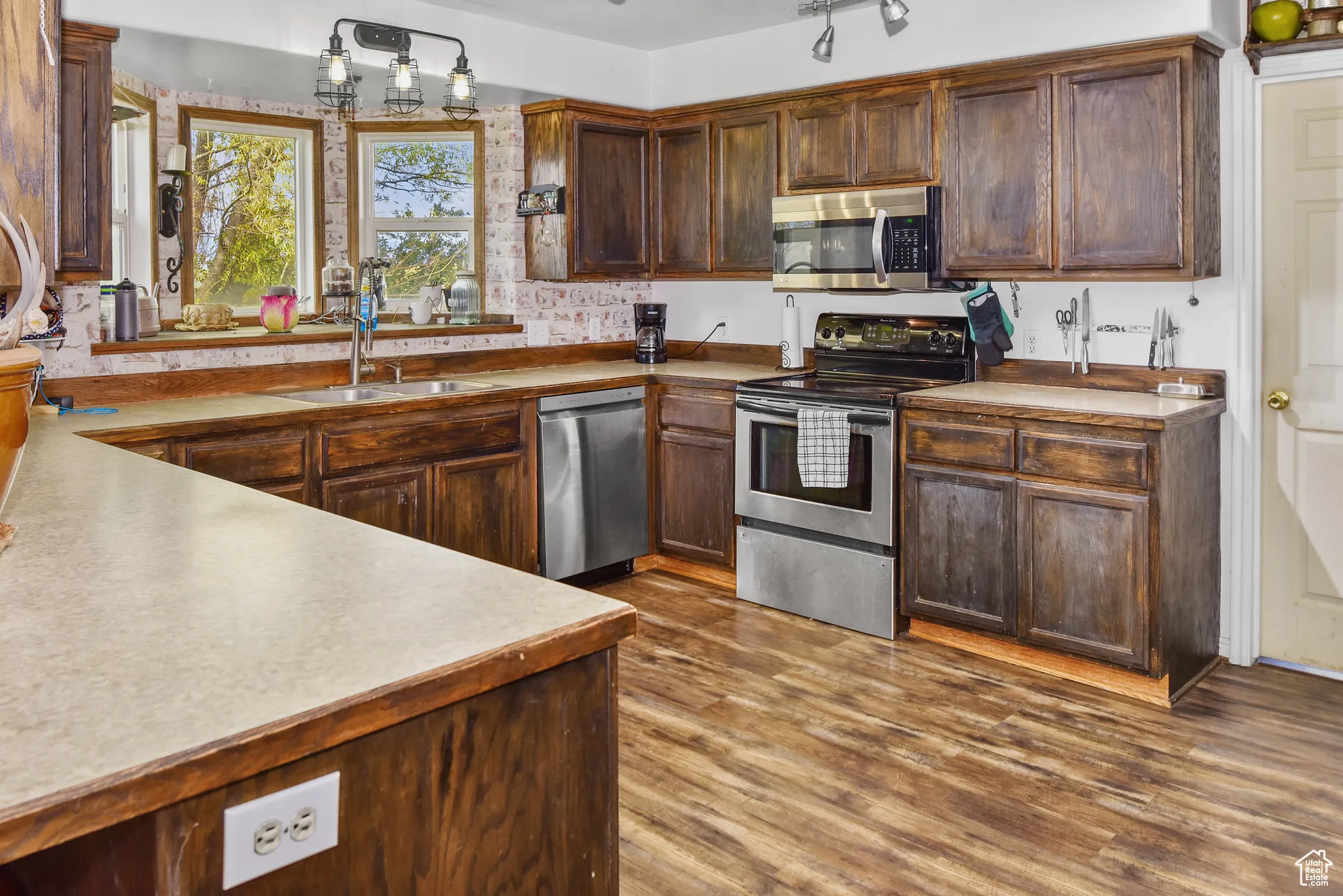 Kitchen featuring appliances with stainless steel finishes, dark wood finished floors, light countertops, and dark brown cabinetry