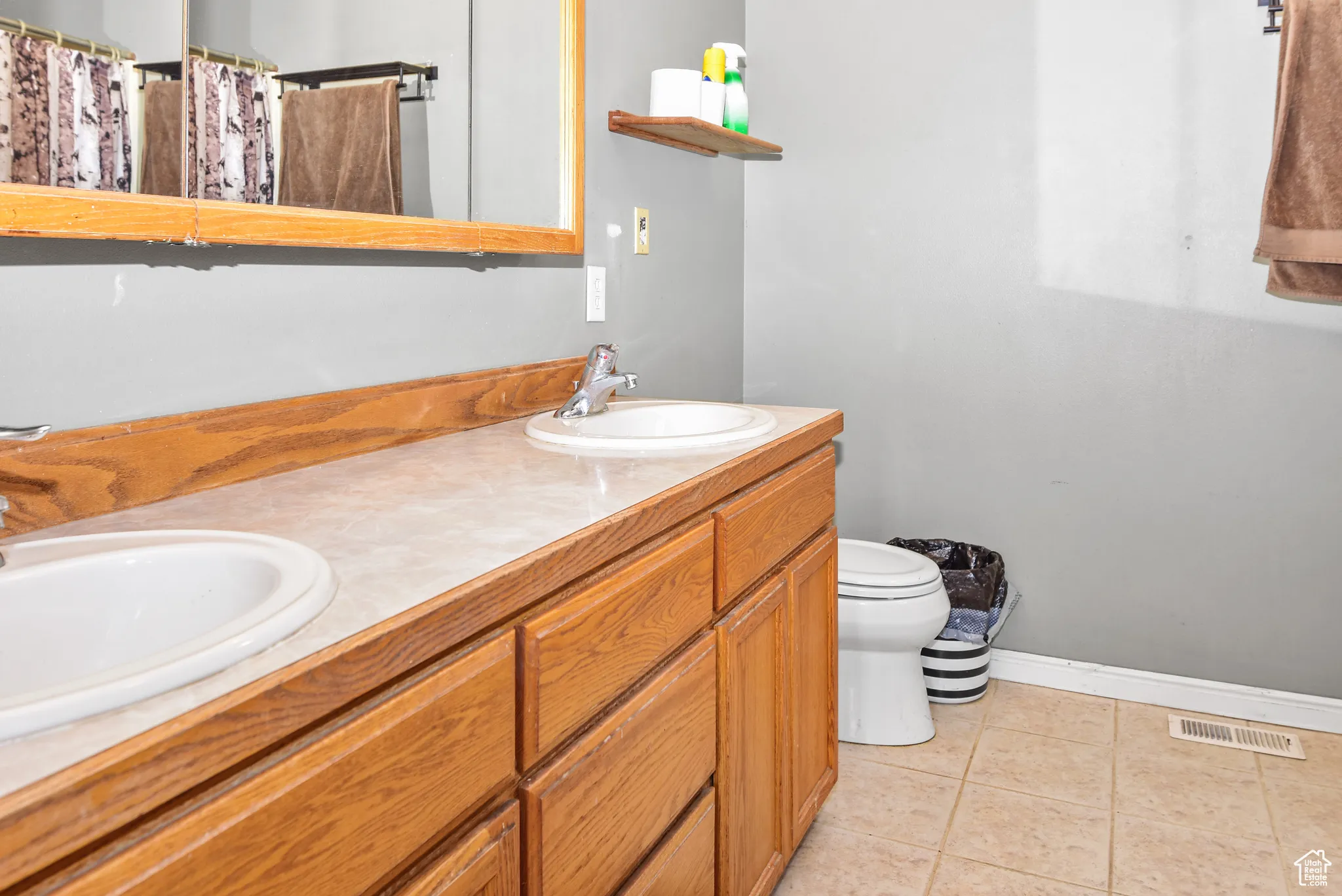 Full bathroom featuring double vanity, light tile patterned flooring, and curtained shower