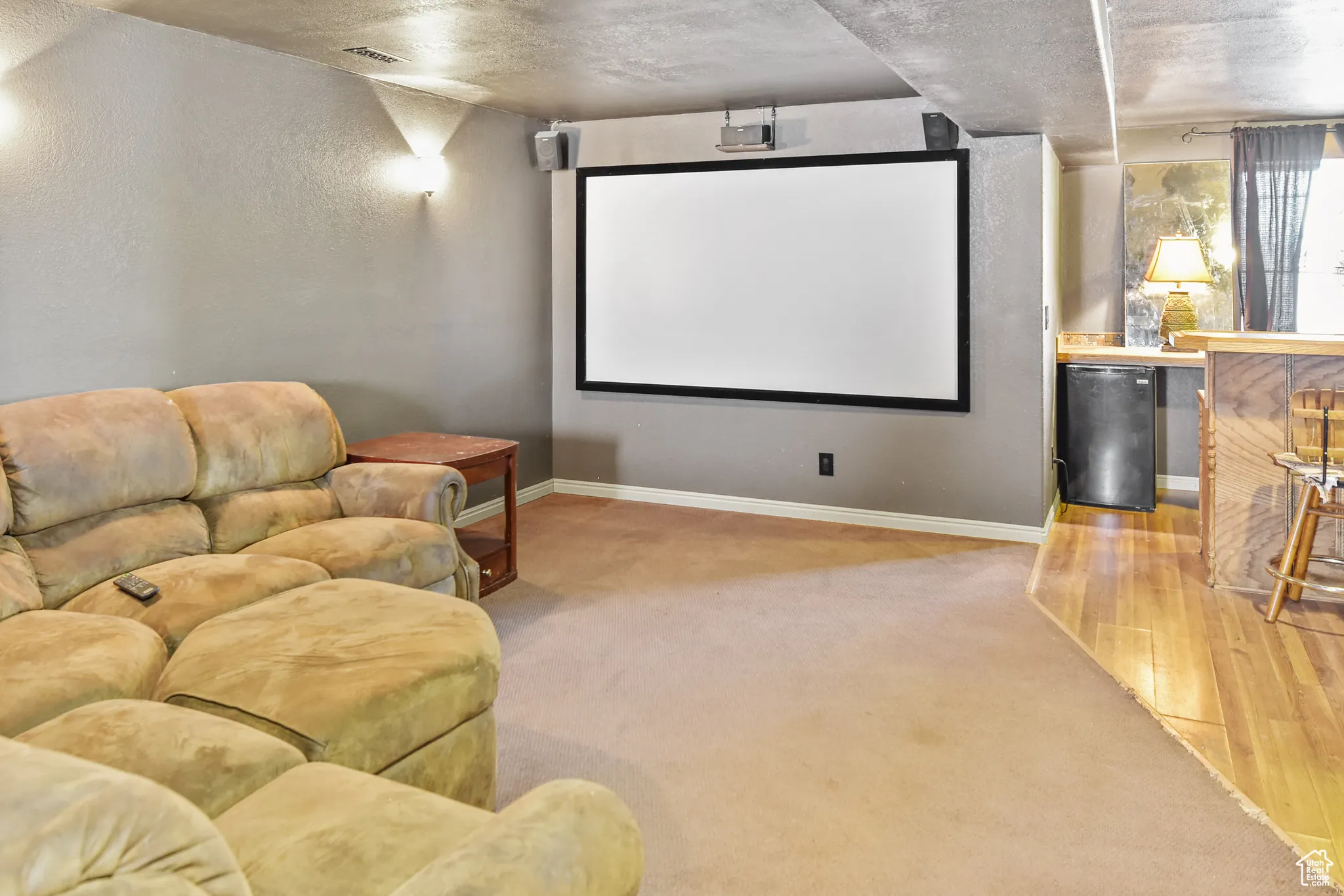 Cinema room featuring light colored carpet, a textured wall, and light wood finished floors