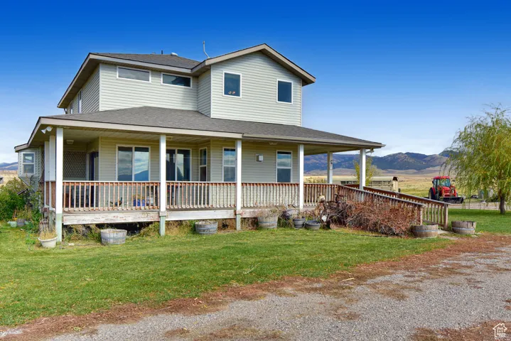 Farmhouse featuring a shingled roof, covered porch, a front yard, and a mountain view