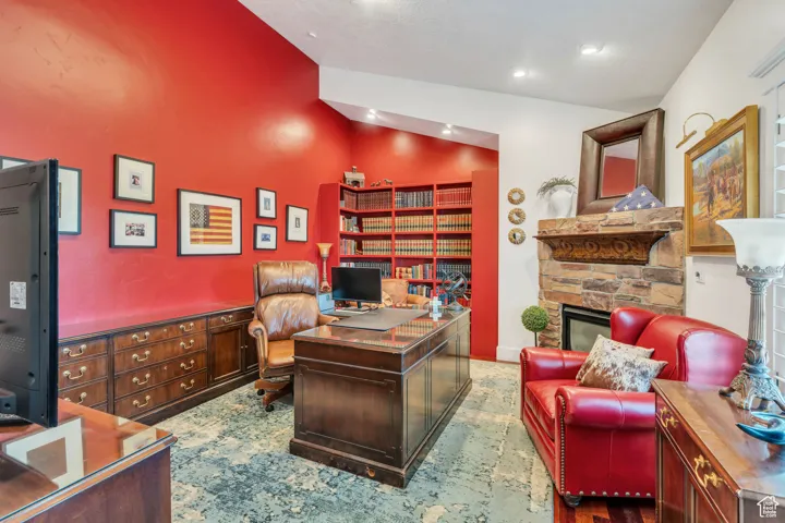 Office area featuring vaulted ceiling and a stone fireplace