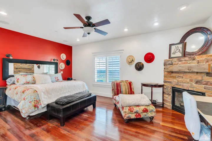 Bedroom featuring wood finished floors, a fireplace, recessed lighting, and ceiling fan