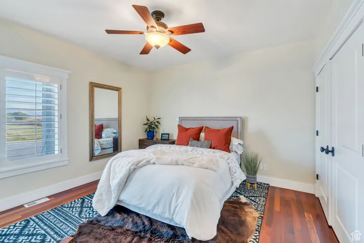 Bedroom with wood finished floors, ceiling fan, and a closet