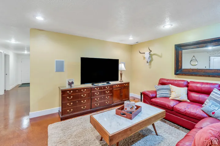 Living room with a textured ceiling, concrete flooring, and recessed lighting