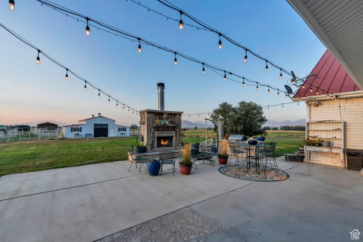 View of patio with a warm lit fireplace and a mountain view