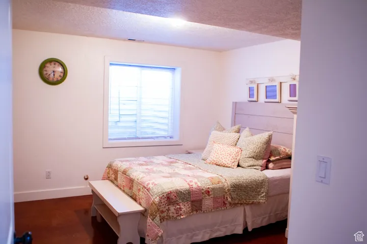 Bedroom with a textured ceiling and dark wood-style floors